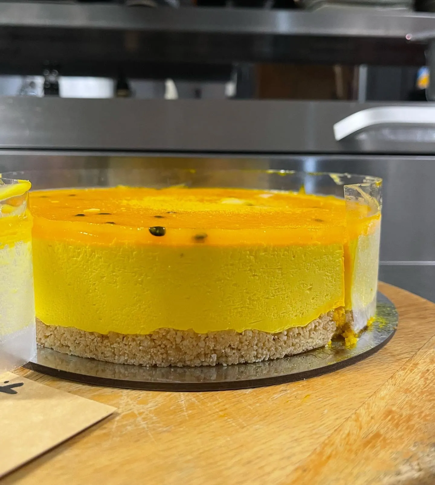 Vibrant mango and passionfruit mousse cake with yellow jelly top layer on a gold cake board
